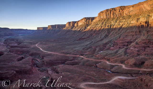 aerial view of a windy road through red sandstone canyon with coarse vegetation near Moab, Utah